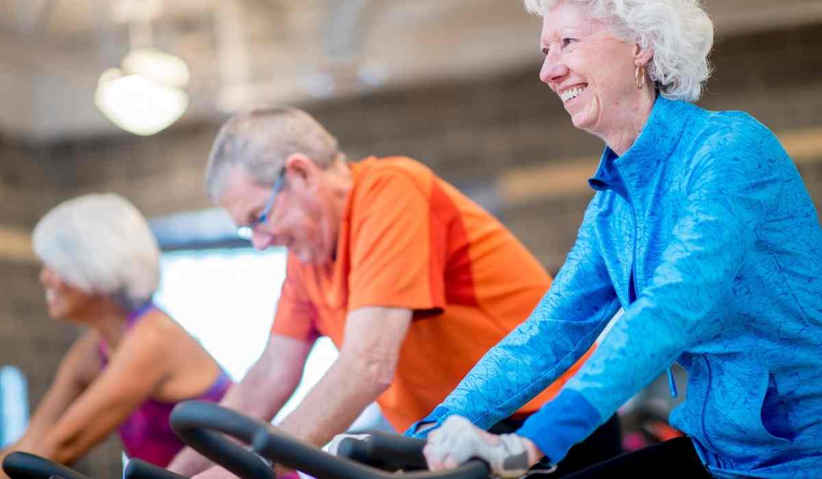 Group of fit seniors on treadmills working out in gym, man smiling