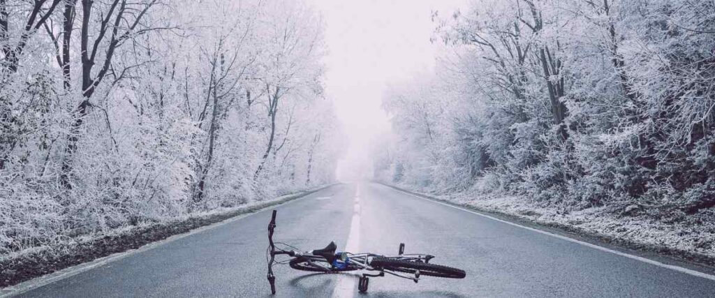 A bike on its side in the middle of a road during winter months. 