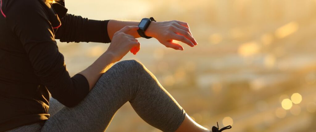 A woman looking at her smart watch before her run.